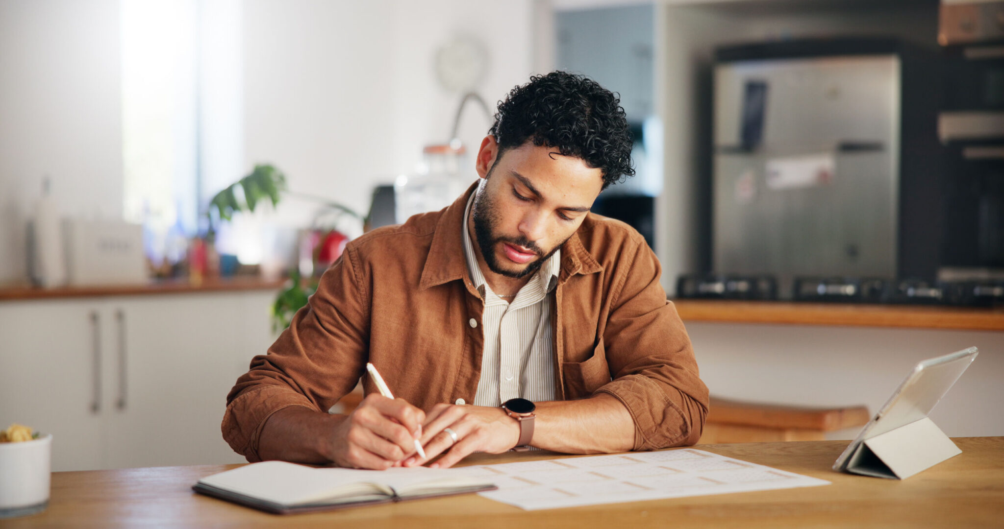 man-writing-and-calendar-planning-in-home-with-ta-2025-04-05-13-09-30-utc_optimized_1000-2048x1080