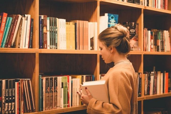 A person taking a book form a library shelf