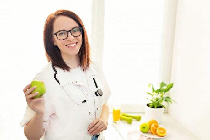 Dietician holding an apple in a clinic