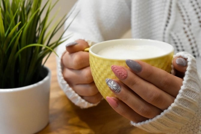 a person with stylish nails holding a cup