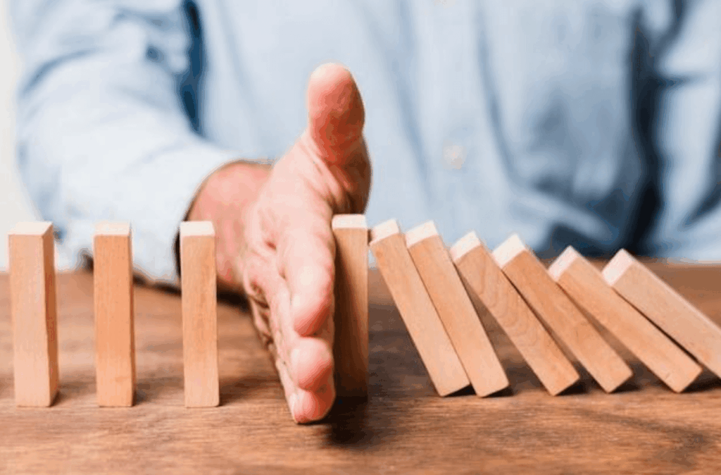 Man stopping falling dominos – roadblock to career growth
