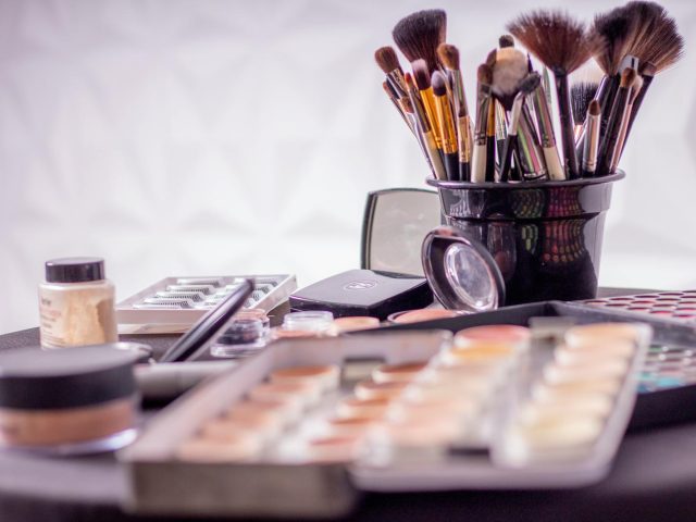Close-up of a professional makeup brush set and cosmetics on a table for beauty use.