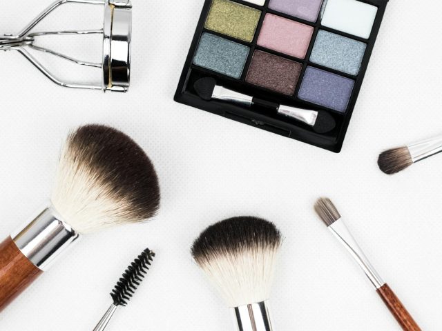 Top view of makeup tools and a colorful eyeshadow palette arranged artistically.