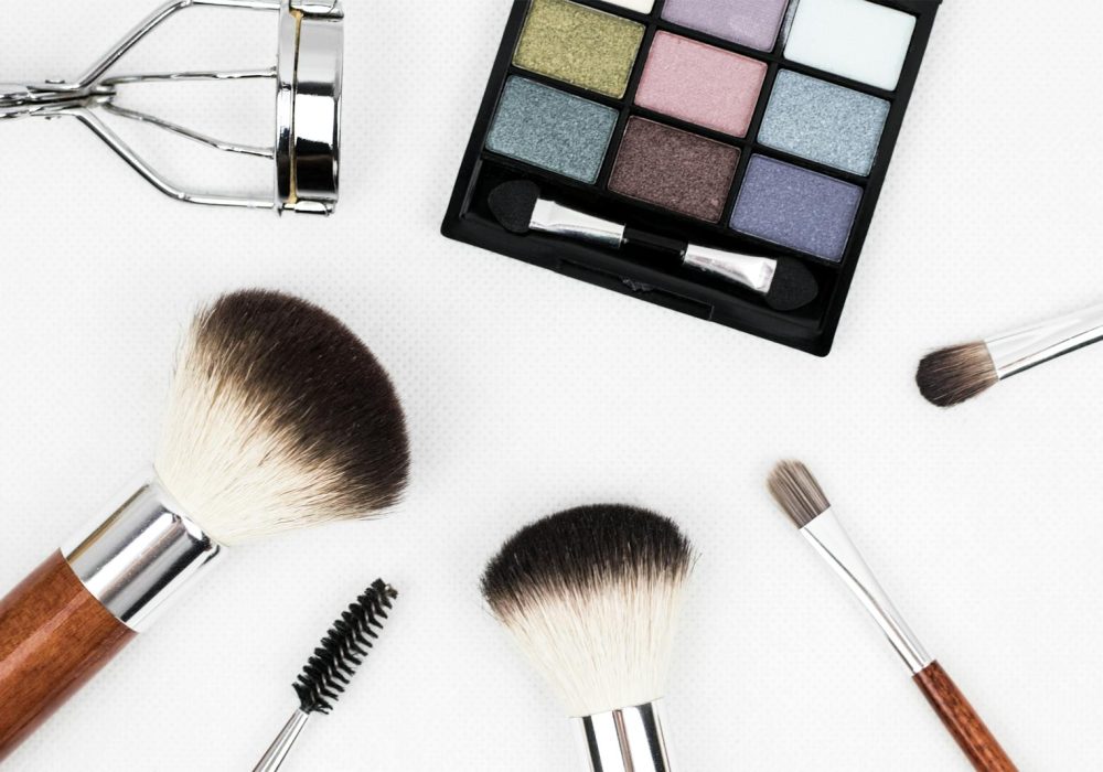 Top view of makeup tools and a colorful eyeshadow palette arranged artistically.