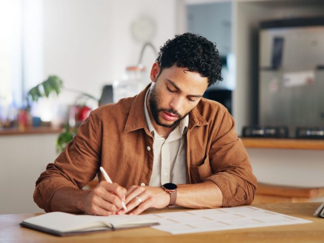 man-writing-and-calendar-planning-in-home-with-ta-2025-04-05-13-09-30-utc_optimized_1000-2048x1080