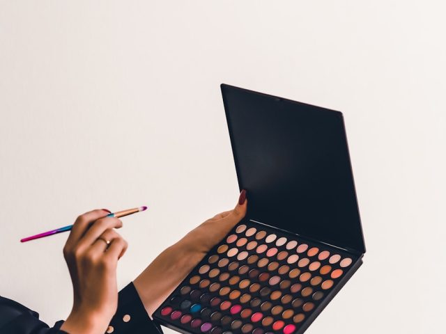 a person holding a makeup palette and a pencil