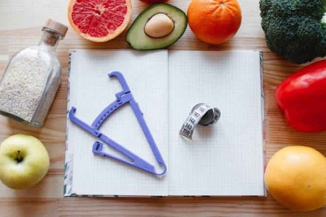 ferramentas para medir em um caderno com alimentos ao seu redor