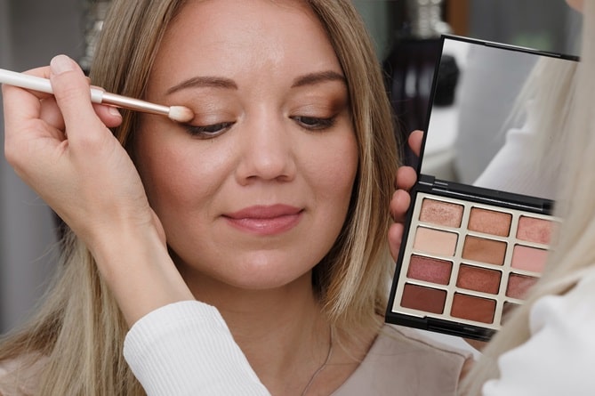 Woman applying nude eye make up
