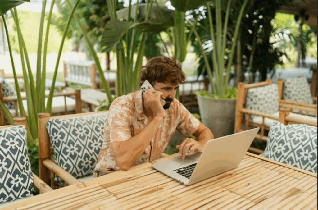 Man working remotely in a tropical location and talking on the phone