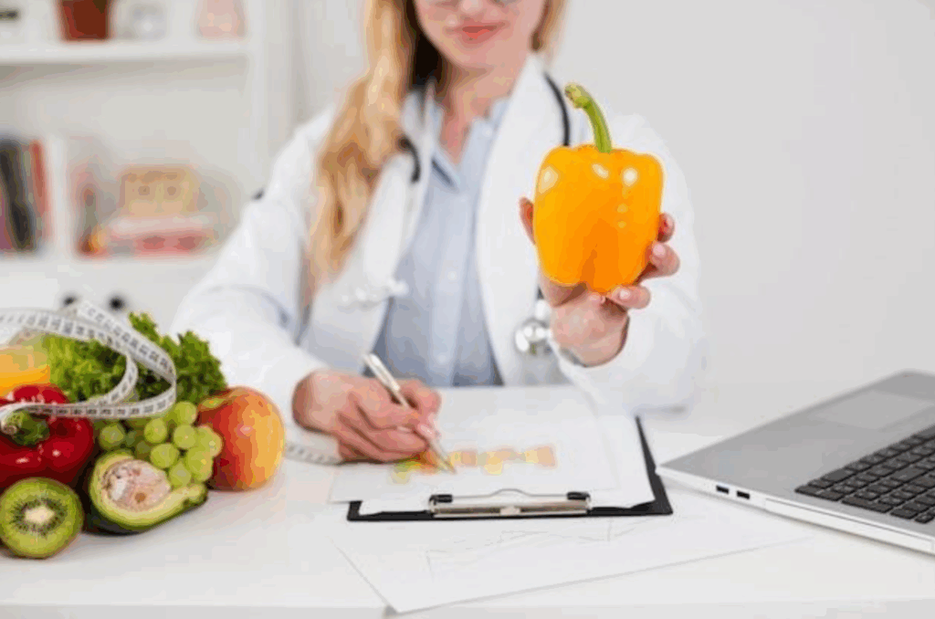 Female nutritionist writing on a chart and holding a bell pepper in an office