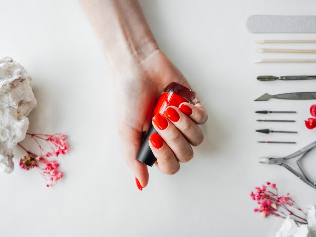 Manicured woman's nails with red nail polish.